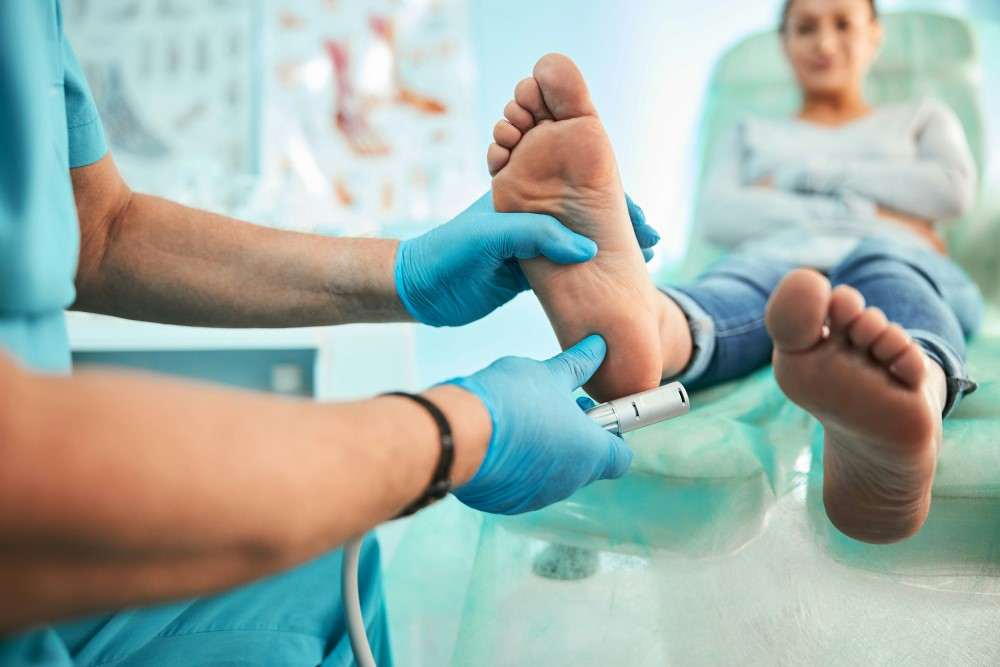 Podologue inspectant un pied de diabétique avec mycose à l'ongle de pied