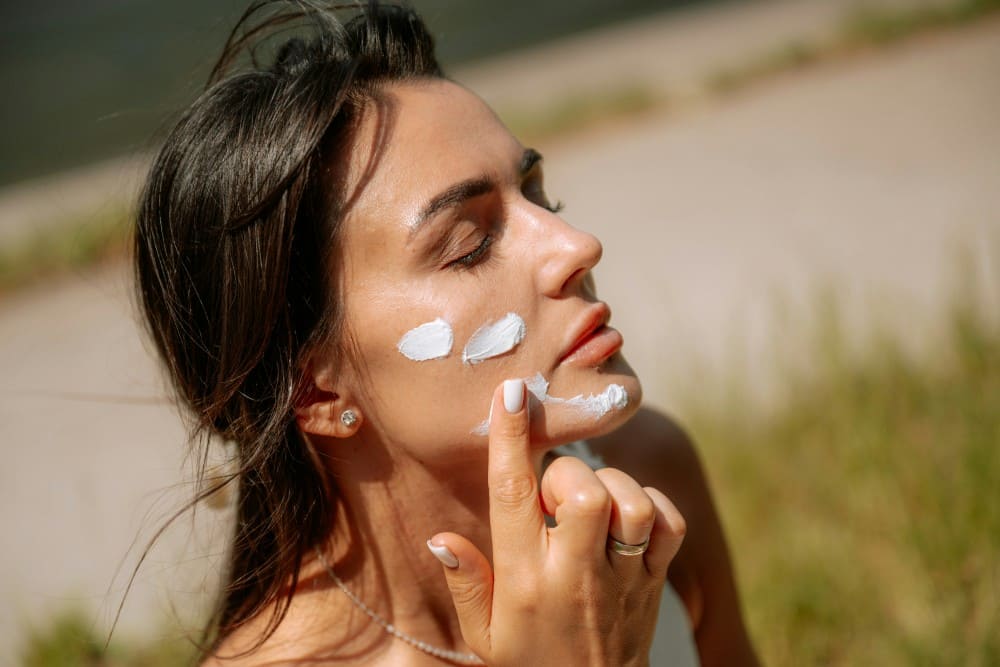 Femme mettant de la crème solaire sur son visage