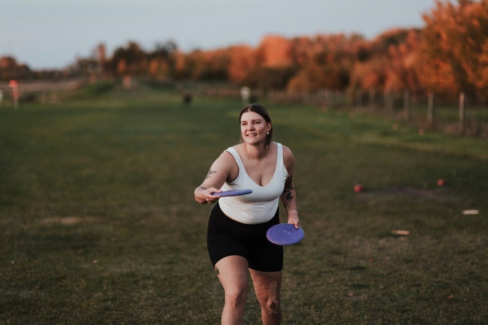 Femme ronde qui fait du frizbi dans un champ