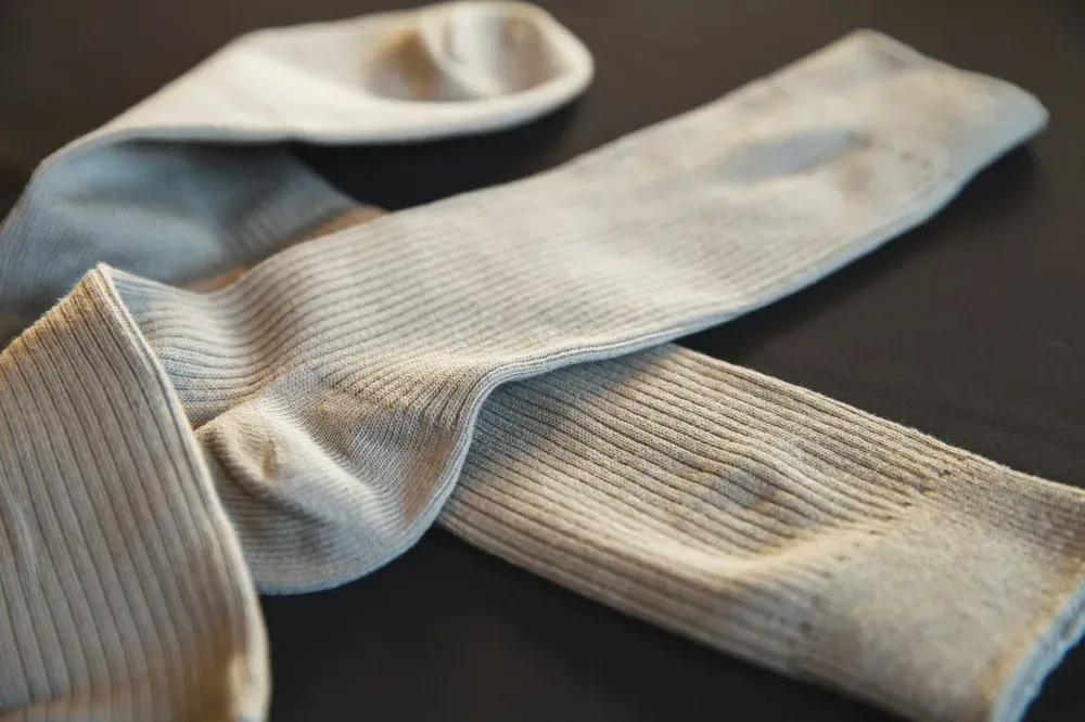 Bas et chaussettes en textile gris disposés sur une surface sombre
