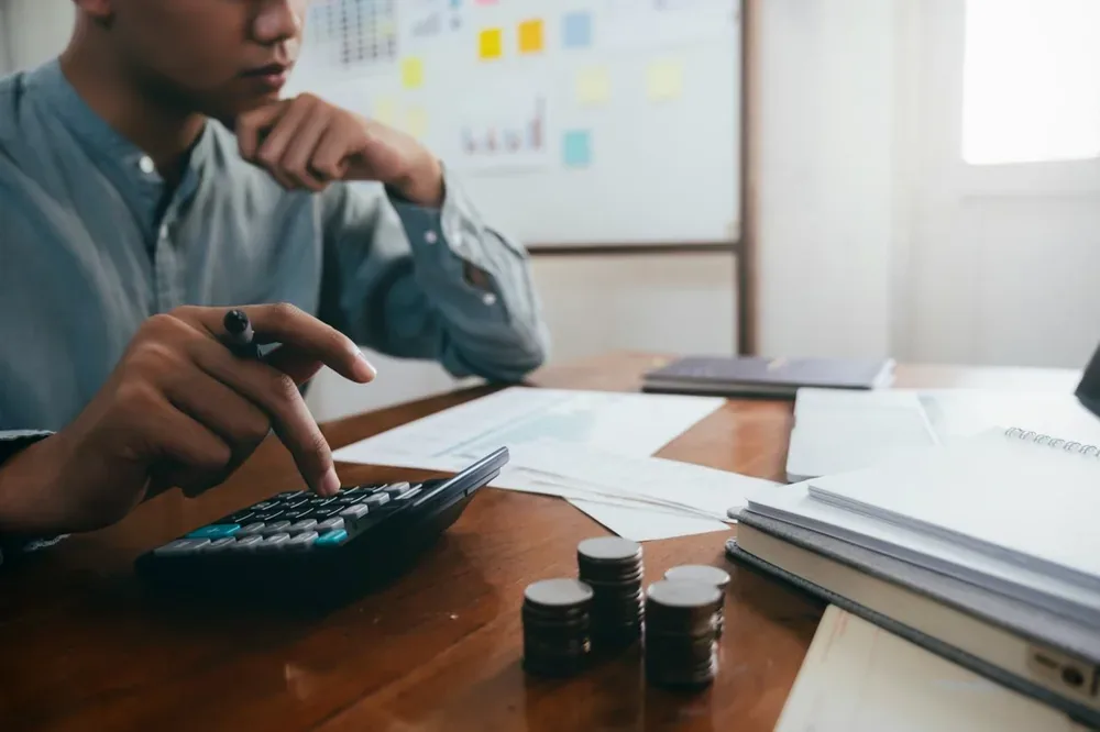 Homme utilisant une calculatrice à côté de documents financiers