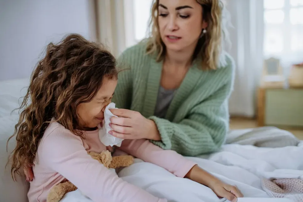 Une mère accompagne une enfant malade à domicile, dans un contexte de nez bouché.
