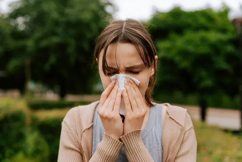 Symptômes Covid 2026 : une femme se couvre la bouche avec un mouchoir en papier.