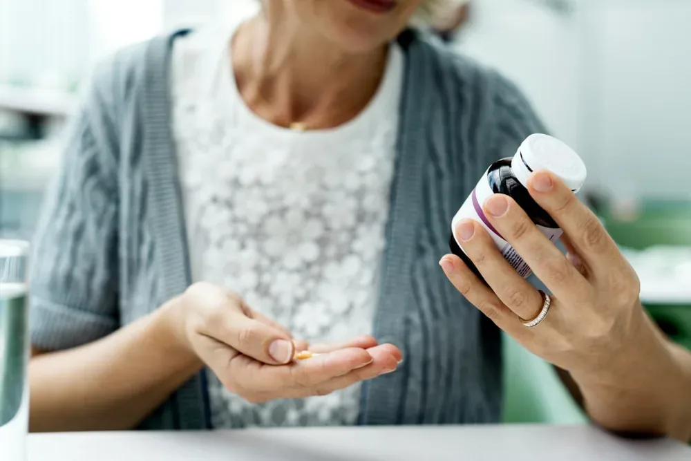 Personne tenant un flacon et un comprimé de médicament