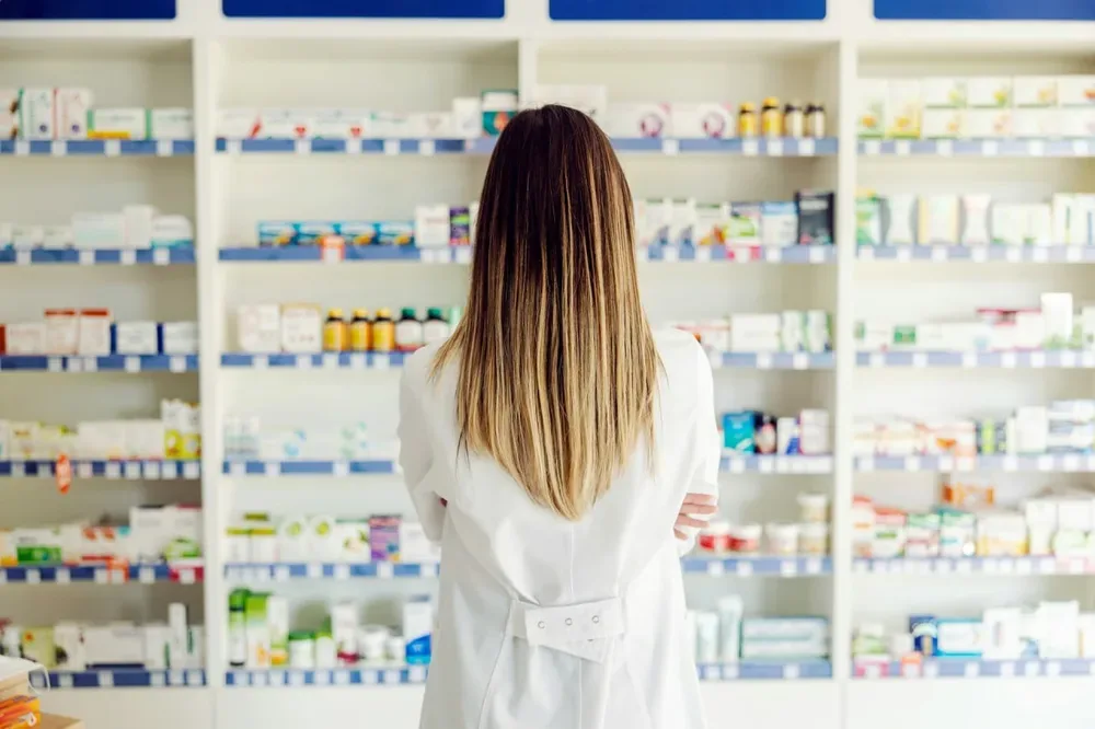 Pharmacienne de dos devant des rayonnages de médicaments